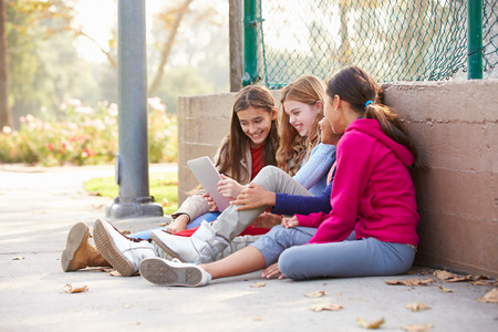 Group Of Young Girls Using Digital Tablet In Parkの写真素材