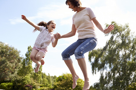 Mother And Daughter Bouncing On Trampoline Togetherの写真素材