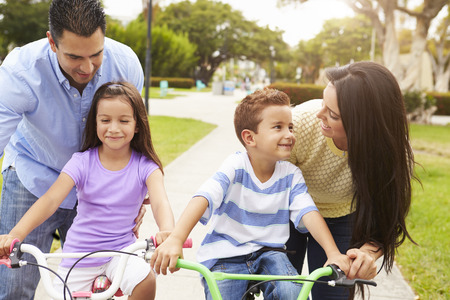 Parents Teaching Children To Ride Bikes In Park