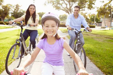 Parents With Daughter Riding Bikes In Parkの写真素材