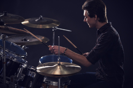 Side View Of Young Drummer Playing Drum Kit In Studioの写真素材
