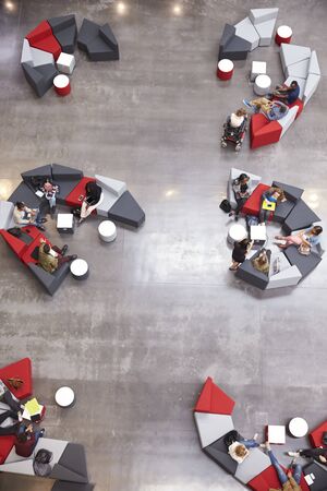 Students groups sit in a modern university atrium, verticalの写真素材