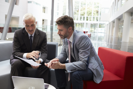 Two Businessmen Meeting In Lobby Area Of Modern Officeの写真素材