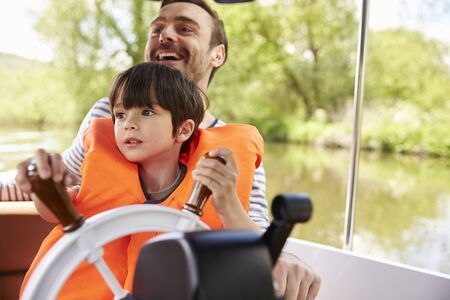Father And Son Enjoying Day Out In Boat On River Togetherの写真素材