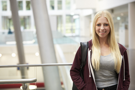 Smiling blonde haired female student in university buildingの写真素材