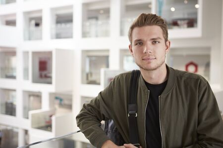 Portrait of young adult male student on mezzanine in universityの写真素材