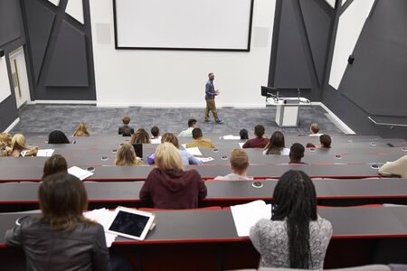 Man lectures students in lecture theatre, back row seat POVの写真素材