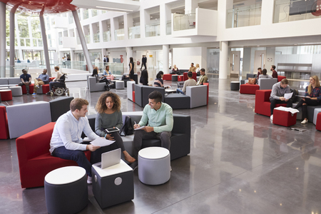 Students sitting in university atrium, three in foregroundの写真素材