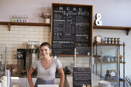 Woman behind the counter of a coffee shop looking to cameraの写真素材