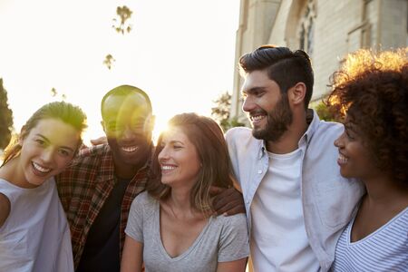 Five happy young adult friends embracing in the streetの写真素材