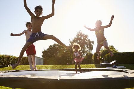 Group Of Children Having Fun Jumping On Outdoor Trampolineの写真素材