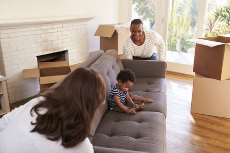 Parents Carry Son On Sofa Into New Home On Moving Dayの写真素材