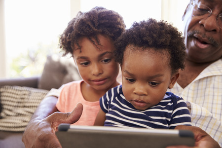 Grandfather And Grandchildren At Home Using Digital Tabletの写真素材