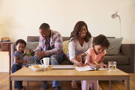 Family Sitting On Sofa As Daughter Colors In Picture Bookの写真素材