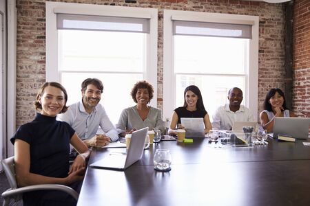 Portrait Of Businesspeople Sitting Around Boardroom Tableの写真素材