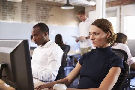 Businesspeople Working At Computers In Busy Modern Office