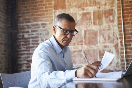Mature Businessman Working On Laptop In Boardroomの写真素材