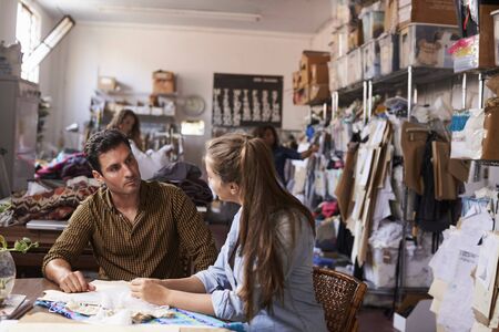 Male manager training apprentice at a clothing design studio