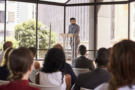 Hispanic man presenting business seminar leaning on lecternの写真素材