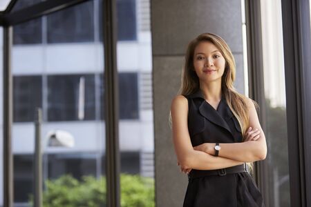 Young Asian businesswoman looking to camera, arms crossed