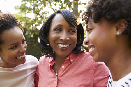 Black mother and two adult daughters in garden, close upの写真素材
