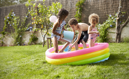 Children Having Fun In Garden Paddling Pool