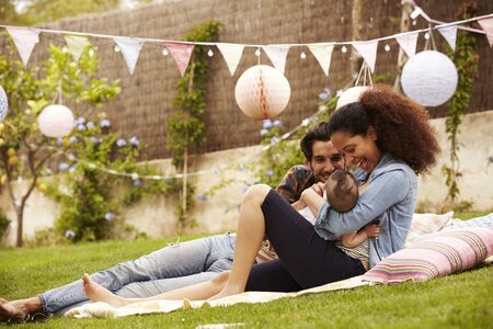 Family With Baby Relaxing On Rug In Garden Togetherの写真素材