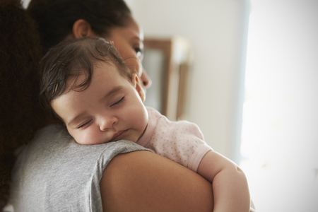 Close Up Of Mother Cuddling Sleeping Baby Daughter At Homeの写真素材