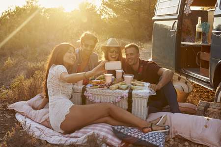 Friends taking a selfie at a picnic beside their camper vanの写真素材