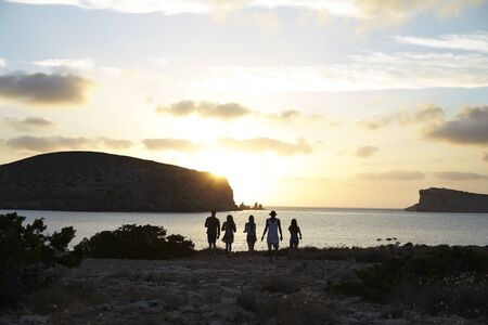 Rear View Of Friends Standing On Cliff Watching Sunset