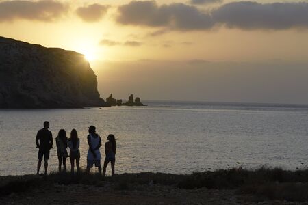 Rear View Of Friends Standing On Cliff Watching Sunsetの写真素材