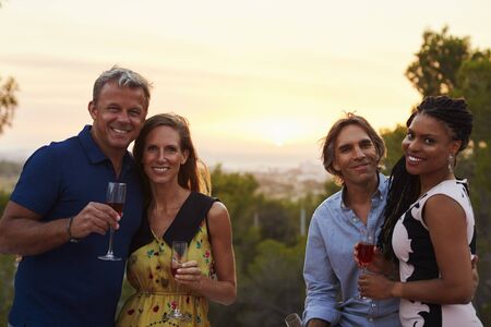 Two happy adult couples socialising outdoors look to cameraの写真素材