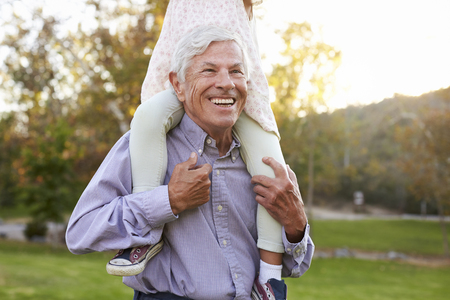 Grandfather Giving Granddaughter A Shoulder Ride In Parkの写真素材