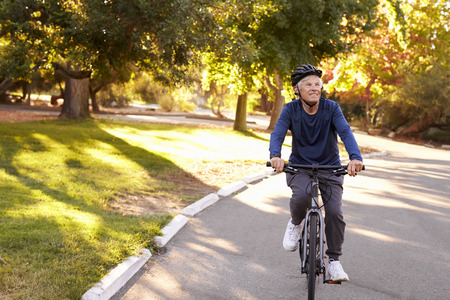 Front View Of Senior Man Cycling Through Parkの写真素材