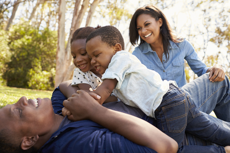 Parents Playing With Children On Grass In Summer Parkの写真素材