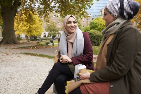 Two British Muslim Women Eating Lunch In Park Togetherの写真素材