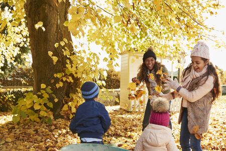 Children Helping Mother To Collect Autumn Leaves In Gardenの写真素材
