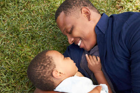 Father Playing With Young Son On Grass In Summer Parkの写真素材