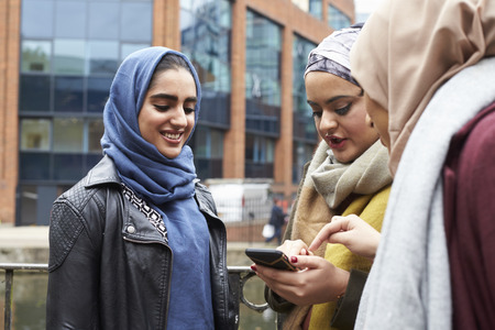 Muslim Female Friends Using Mobile Phone In Urban Settingの写真素材