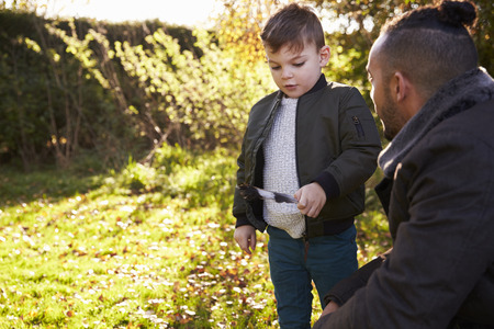 Boy And Father Playing With Feather In Autumn Gardenの写真素材