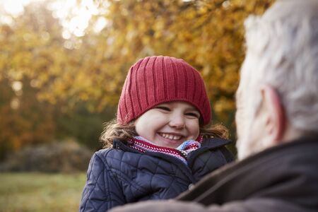 Grandfather Cuddling Granddaughter On Autumn Walkの写真素材