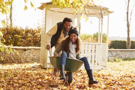 Man In Autumn Garden Gives Woman Ride In Wheelbarrowの写真素材
