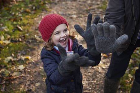 Granddaughter Wearing Grandfather's Gloves On Autumn Walkの写真素材