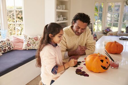 Father And Daughter Making Halloween Decorations At Homeの写真素材