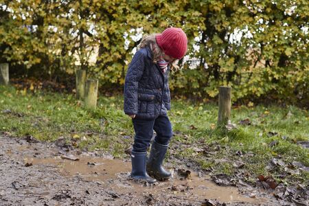 Girl Splashing In Puddle On Winter Walkの写真素材