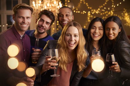 Group portrait of friends with drinks enjoying house party