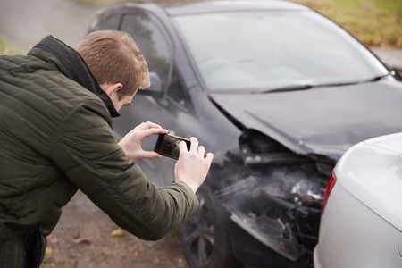 Man Taking Photo Of Car Accident On Mobile Phoneの写真素材