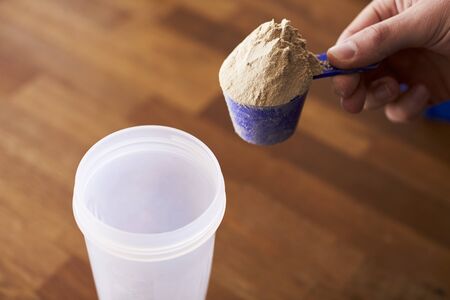 Close Up Of Man Mixing Protein Shake In Cupの写真素材