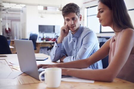 Man and woman working together at a desk in open plan office