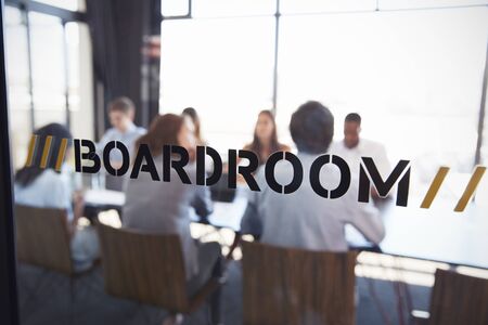Team in a boardroom meeting, defocussed through glass wallの写真素材